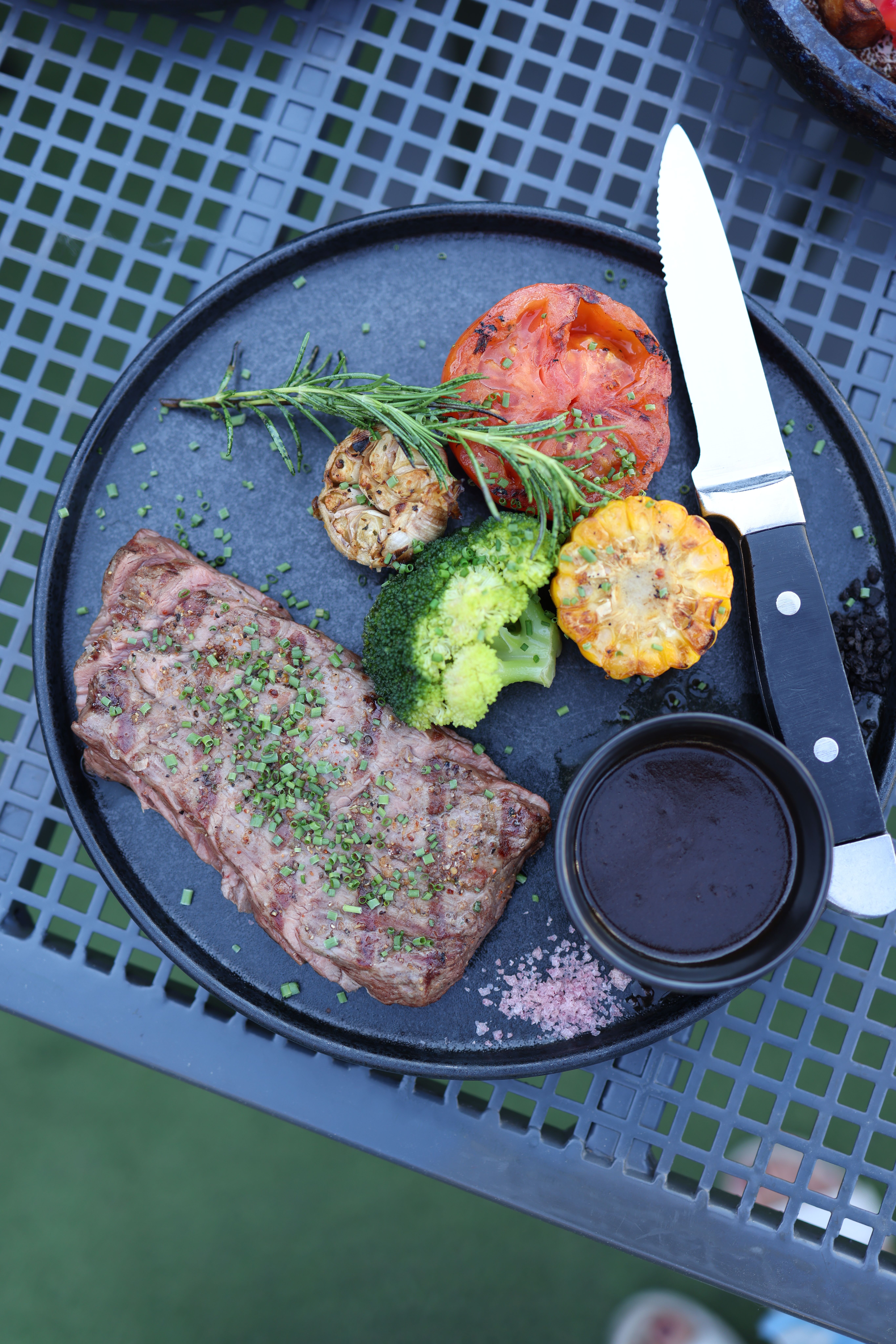 A delicious grilled steak served with vegetables and sauce on a plate.