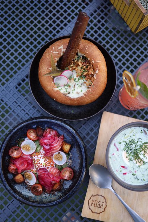 Free Elegant gourmet lunch setup with bread bowl, salad, and refreshing drink on outdoor table. Stock Photo
