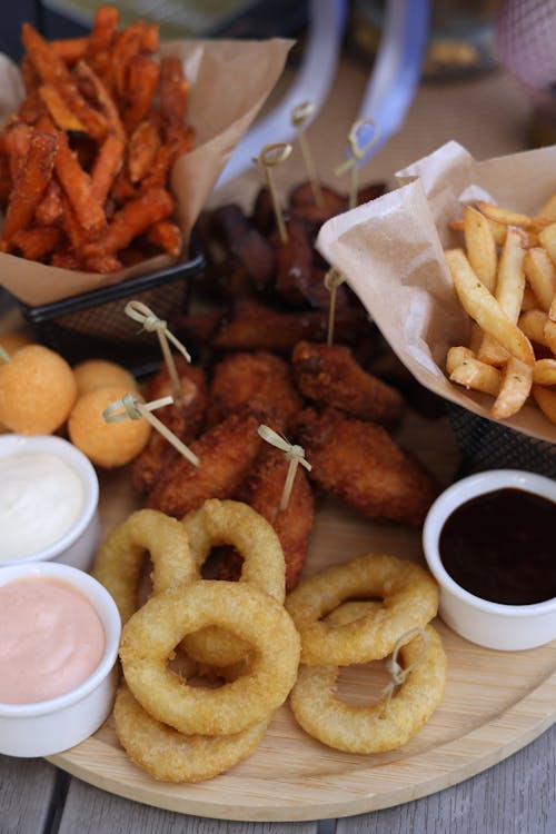 A wooden tray with fried food and dipping sauce