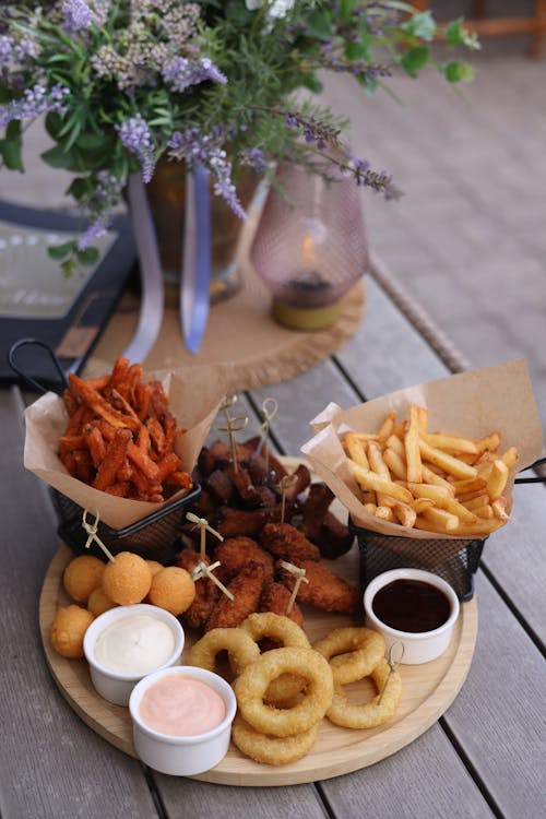 A wooden table with a plate of food and a basket of fries