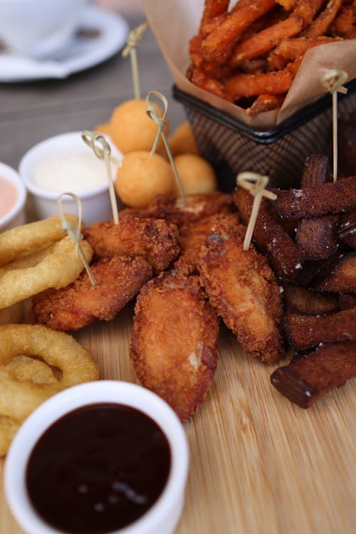 A wooden cutting board with fried food and dipping sauce