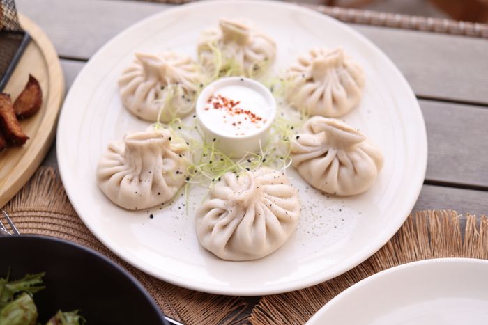 Plate of pleated dumplings with dipping sauce on a wooden table