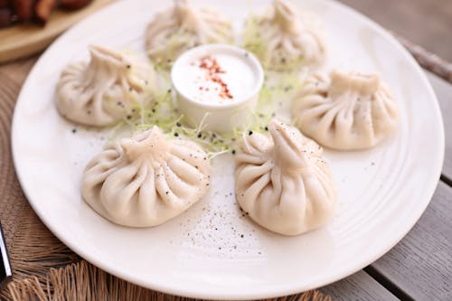 A plate of dumplings with dipping sauce on it