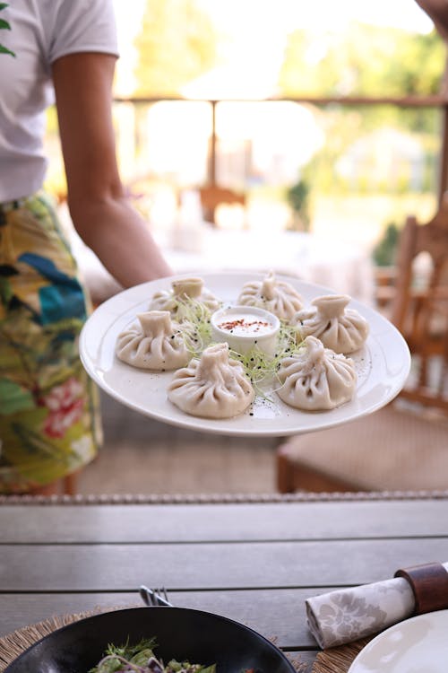 A woman holding a plate of dumplings