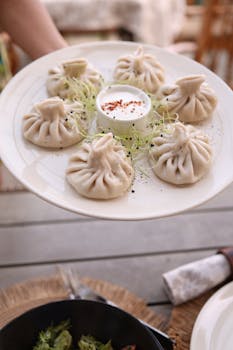 Delicious khinkali dumplings served on a plate with dipping sauce, perfect for foodies.