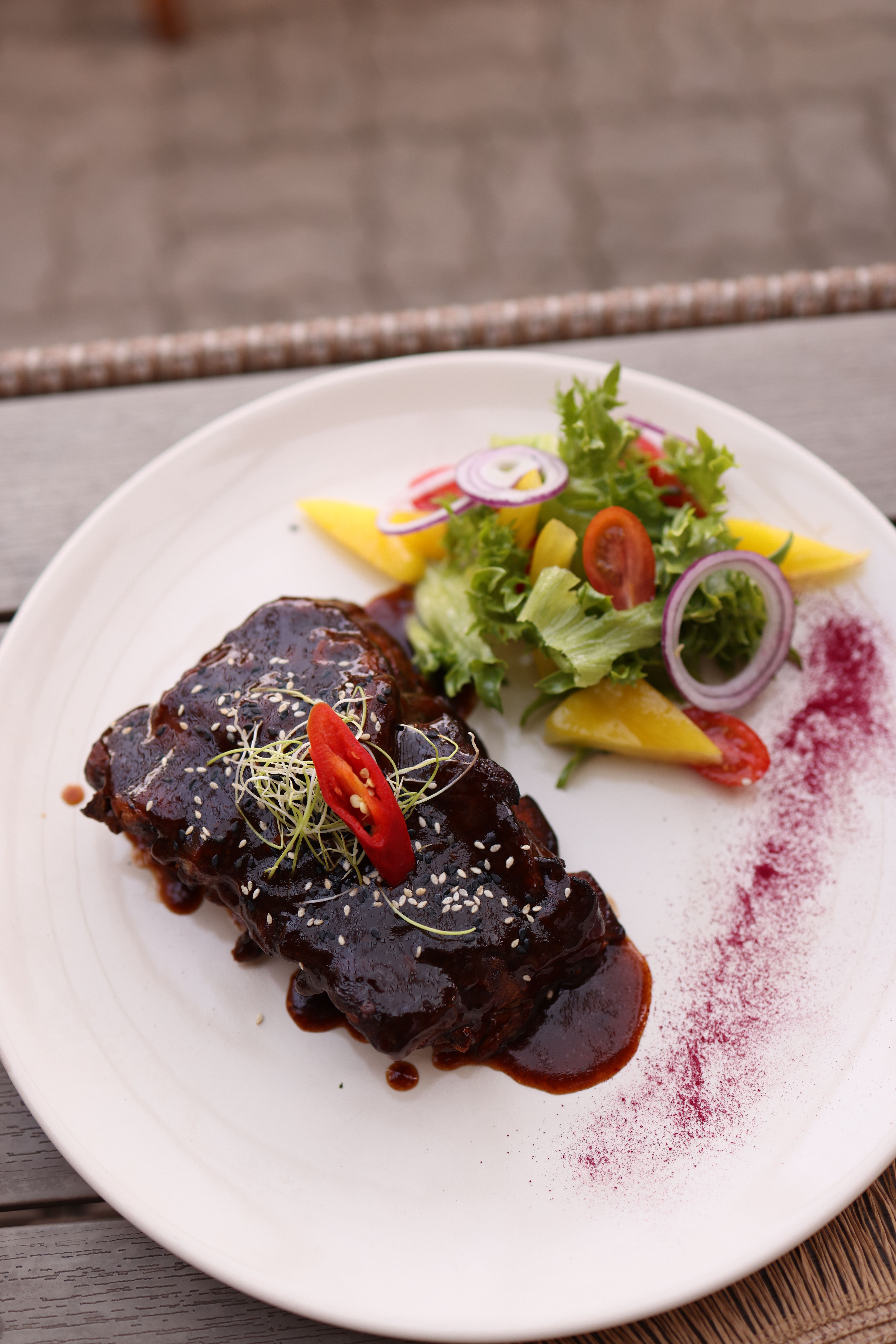 A delicious gourmet meat dish with a fresh and colorful salad, perfect for a restaurant setting.