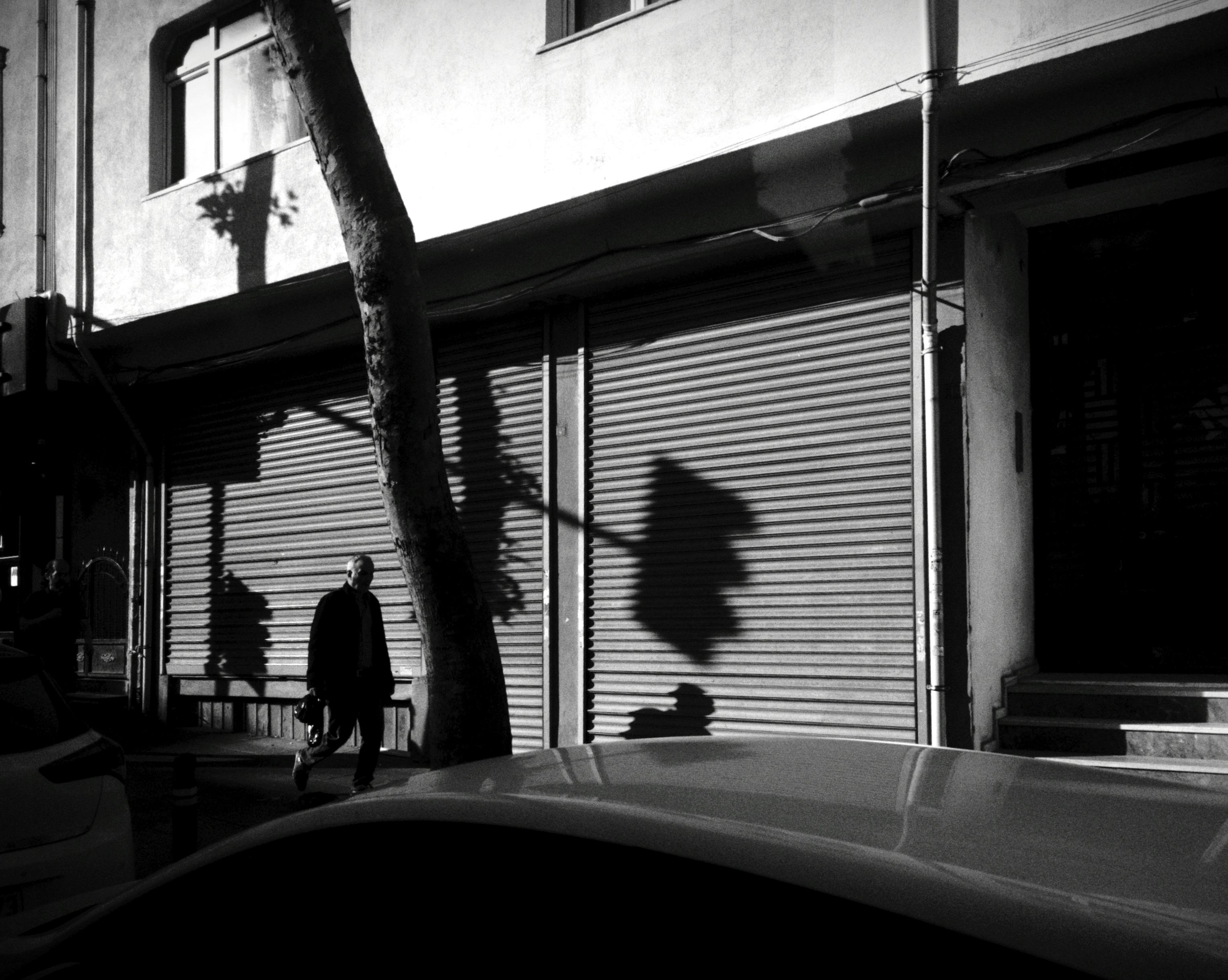 A black and white image capturing a pedestrian walking past a shop in Istanbul, Türkiye.
