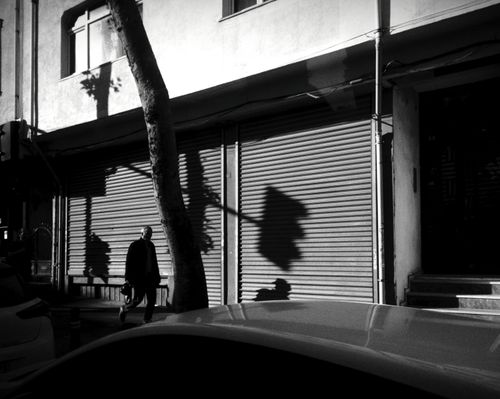 Free A black and white image capturing a pedestrian walking past a shop in Istanbul, Türkiye. Stock Photo