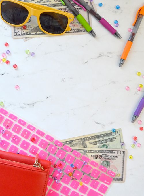Free A vibrant flat lay featuring a pink keyboard, sunglasses, pens, and dollar bills on a desk. Stock Photo