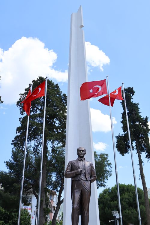 Free Atatürk monument in İzmir, Türkiye, surrounded by waving Turkish flags under a clear sky. Stock Photo