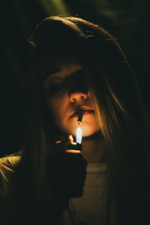 A woman holding a cigarette in the dark