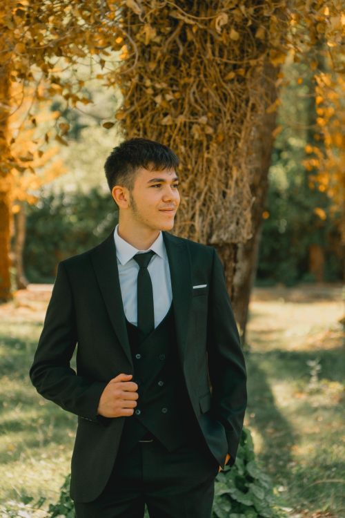 Free A young man in a suit posing outdoors with autumn foliage in the background. Stock Photo