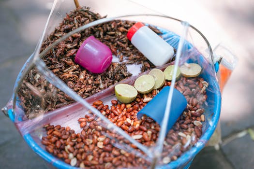 Colorful display of traditional Mexican street snack including peanuts, grasshoppers, and limes.