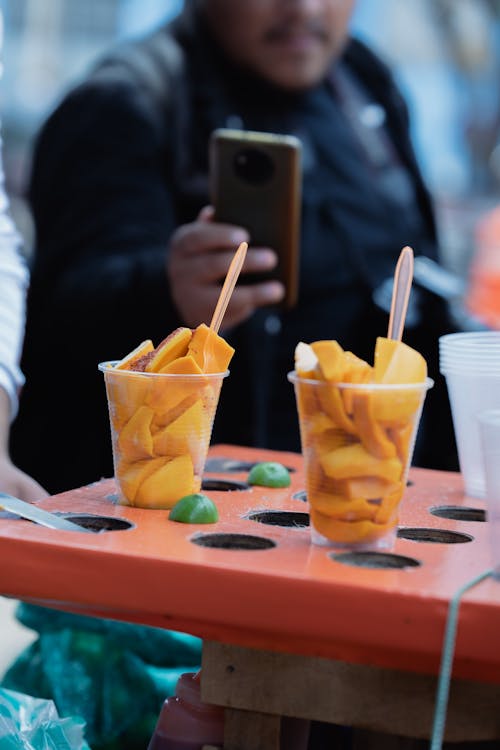 A person taking a picture of a tray of fruit