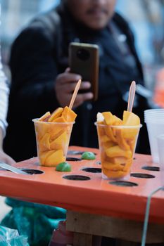Street scene in Mexico City showing fresh mango cups at a food stand.