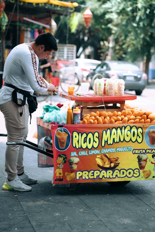 A man pushing a cart with a fruit stand on it