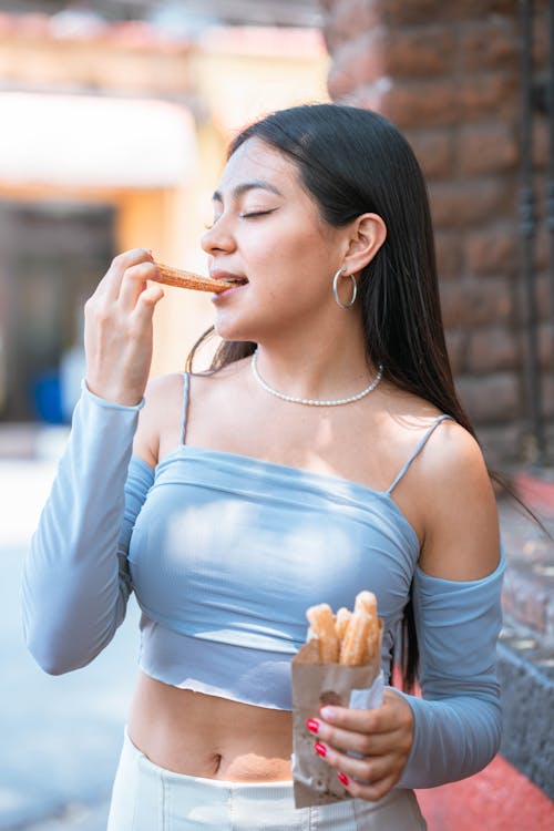 A woman eating french fries and drinking a soda