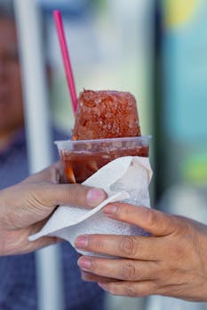 Close-up of hands holding a traditional flavored ice drink in Mexico City, perfect for cooling off during warm days.
