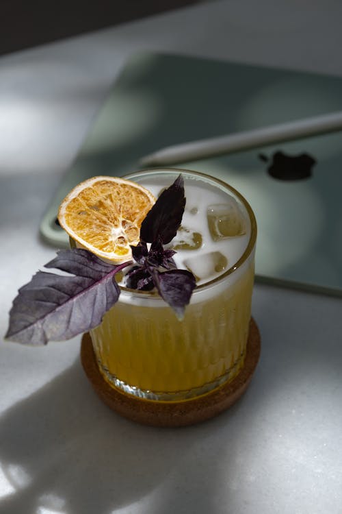 Free A drink with an orange slice and basil leaves Stock Photo