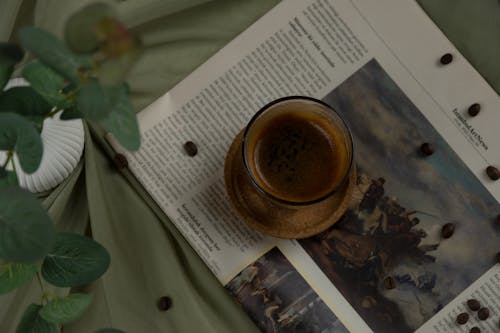 A cup of coffee on a table next to a book