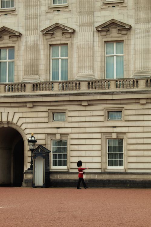 Free Guard in red uniform patrols outside Buckingham Palace, London. Stock Photo