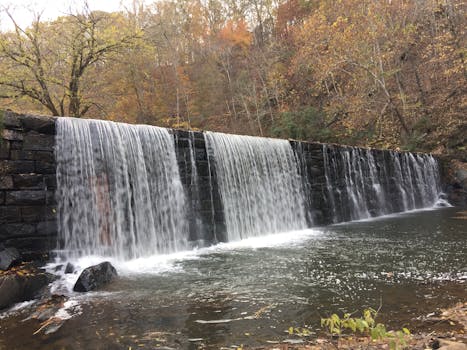 Beautiful waterfall cascading over a stone wall surrounded by fall foliage in Lynchburg, Virginia.