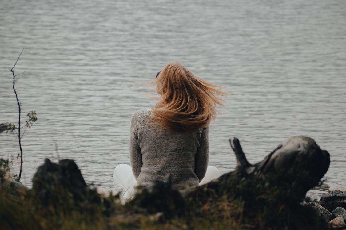 Back View of a Woman Sitting on the Shore · Free Stock Photo