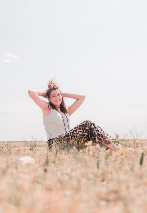 Free Photo of Smiling Woman Sitting on Grass Posing with Her Hands Behind Her Head Stock Photo