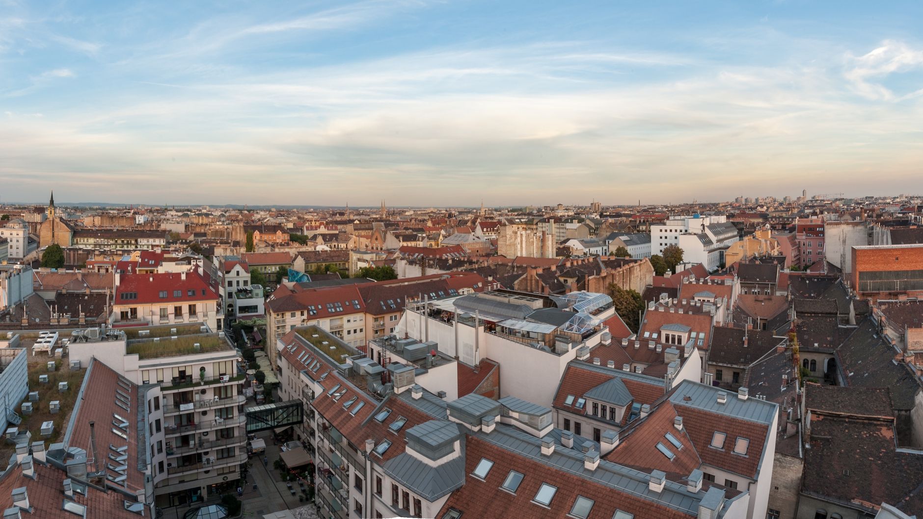 Aerial view of a city's architectural diversity with rooftops under a blue sky.