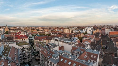 Free Aerial view of a city's architectural diversity with rooftops under a blue sky. Stock Photo