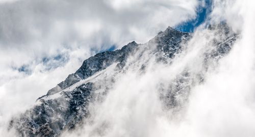 Free Dramatic view of a snow-covered mountain peak enveloped in clouds, highlighting nature's beauty. Stock Photo