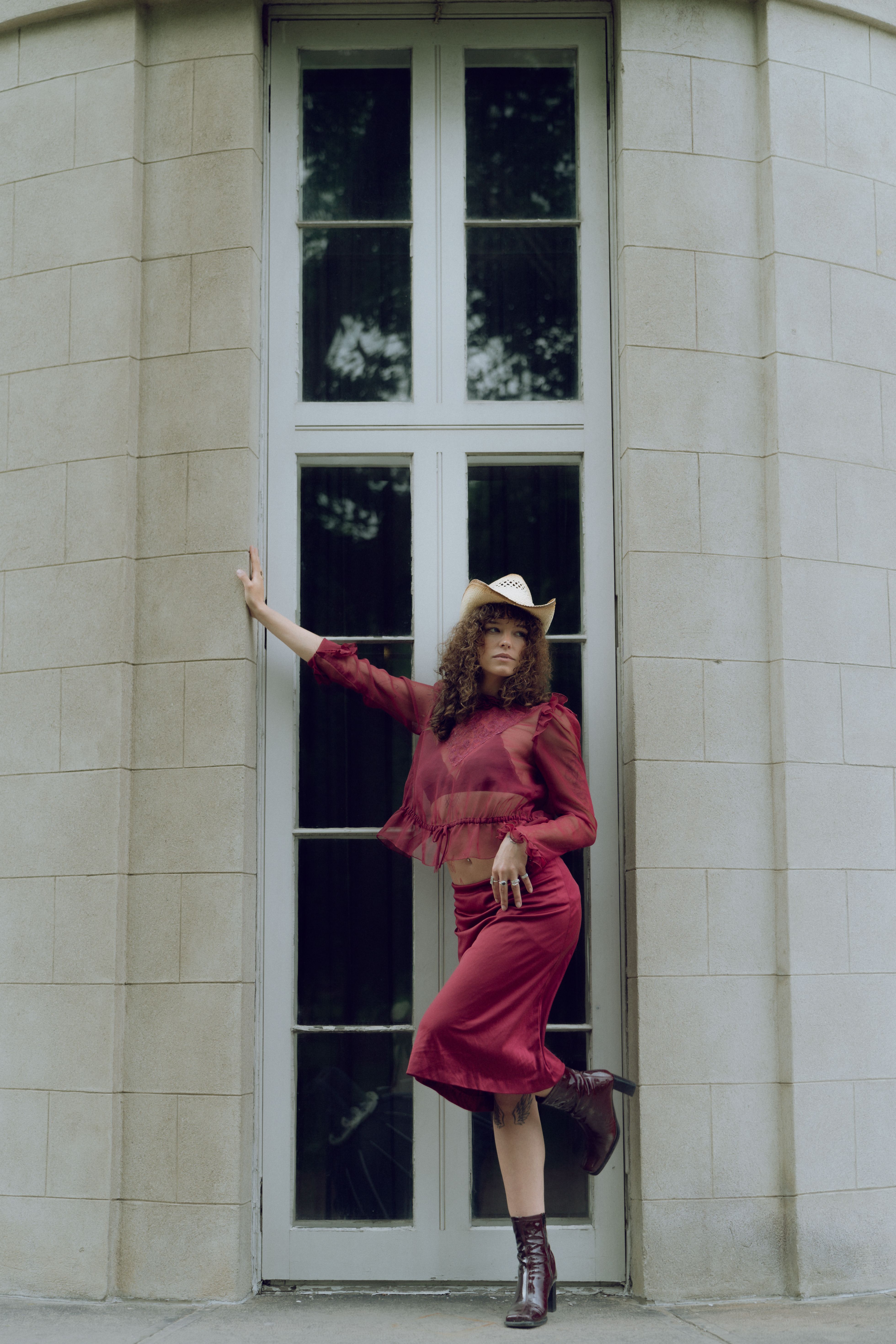 A woman in a red dress and hat leaning against a wall · Free Stock Photo