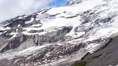 雄伟的雪山覆盖着岩石斜坡，呈现出戏剧性的冰川景色