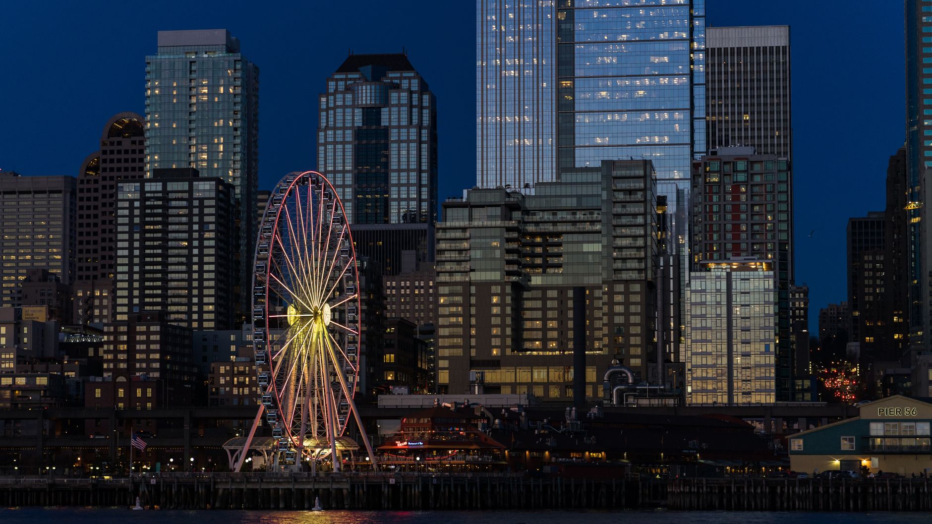 Captivating Seattle skyline with illuminated Ferris wheel and skyscrapers at night.