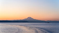 白雪皑皑的山映衬着宁静的日落景色，俯瞰着平静的大海