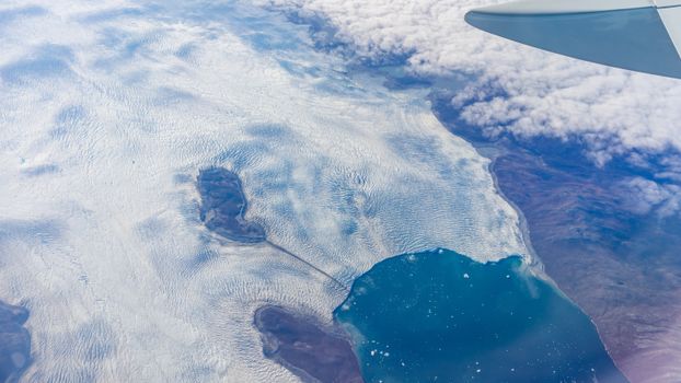 Stunning aerial perspective of glacier meeting ocean as seen from airplane window.