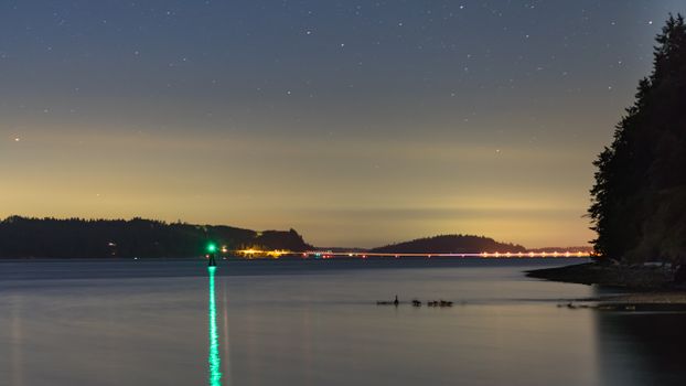 宁静的沿海夜景中，星星与温柔的水面倒影交相辉映