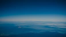 在晴朗的蓝天下，从空中俯瞰，雾霭笼罩的山脉呈现出令人惊叹的景色，捕捉了大自然的宁静之美