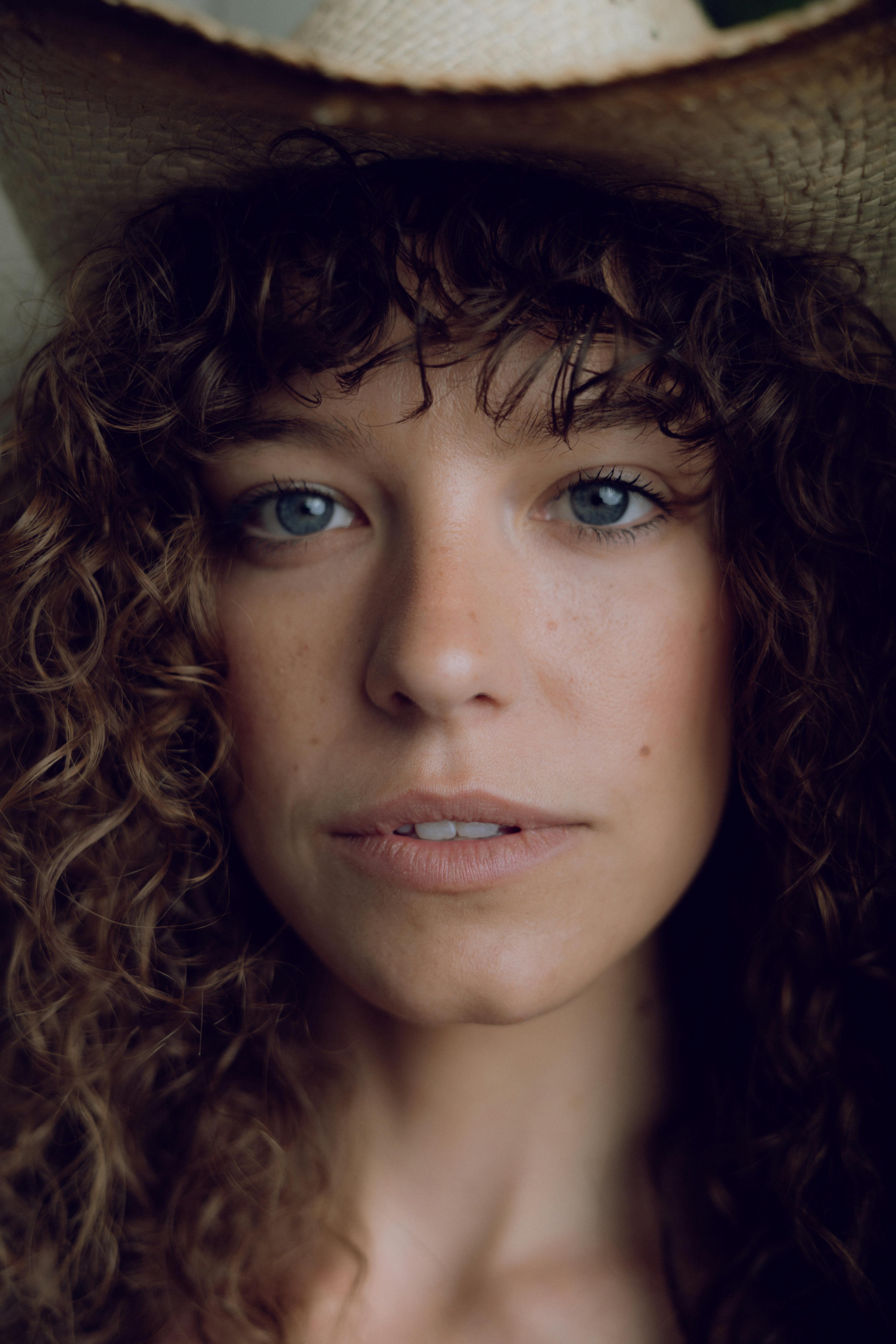 a woman with curly hair and a cowboy hat