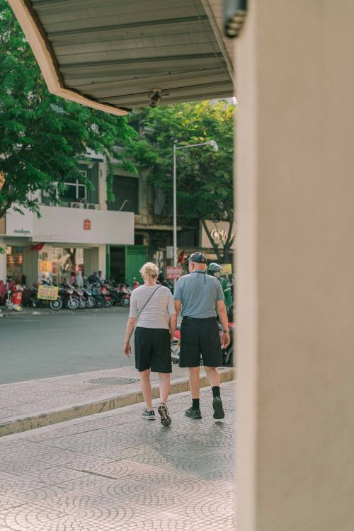 Free An elderly couple strolls down a sidewalk in Ho Chi Minh City, Vietnam, enjoying a sunny day. Stock Photo