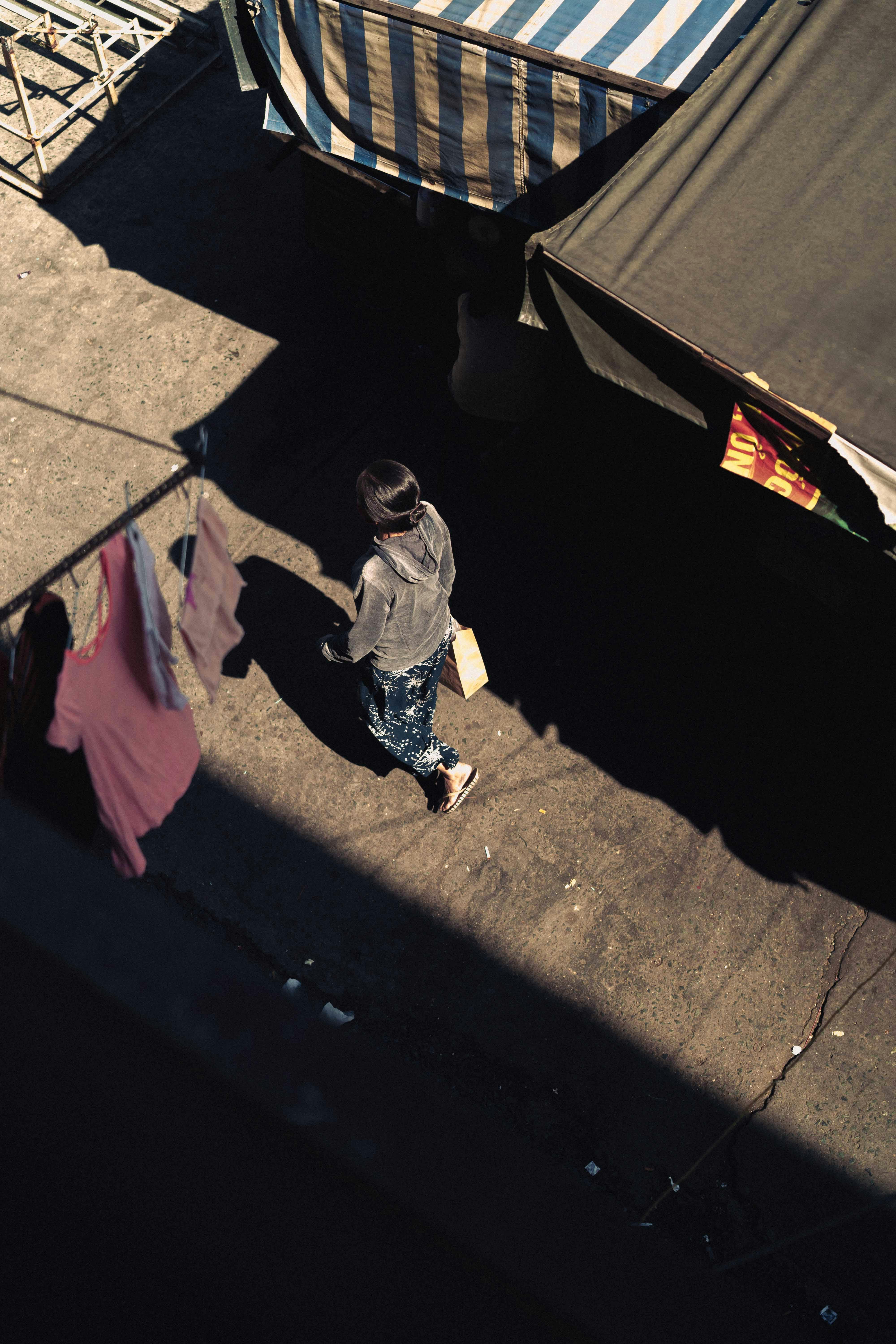 Aerial shot capturing a woman walking through an alley in Ho Chi Minh City, Vietnam.