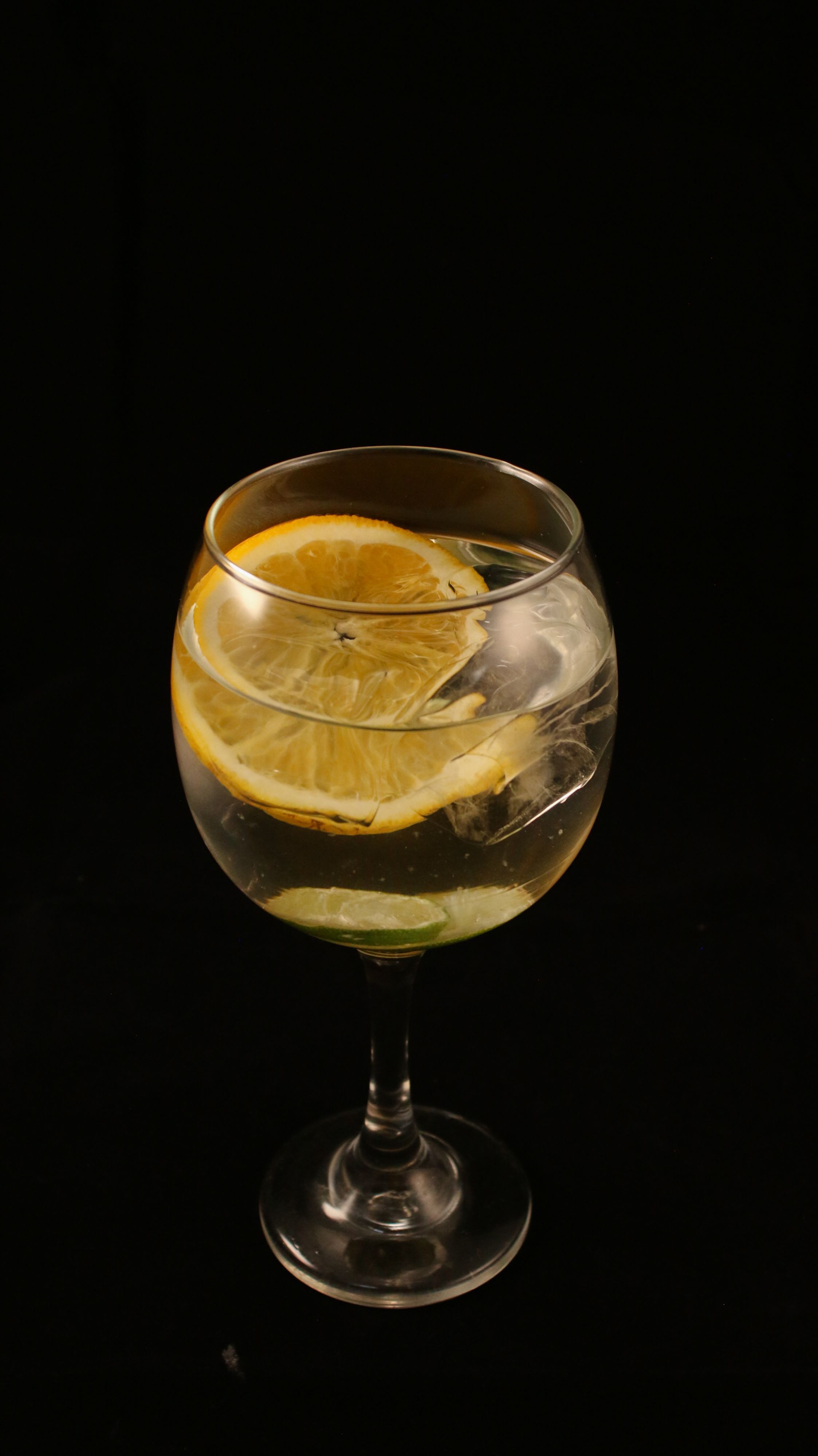 Glass of refreshing lemon drink with ice on a black background, perfect for refreshing concepts.