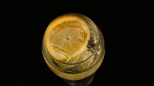 Free A top-down view of a refreshing lemon drink with ice in a glass on a black background. Stock Photo