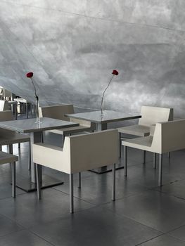 Elegant café setting with sleek tables and chairs accented by single rose stems.