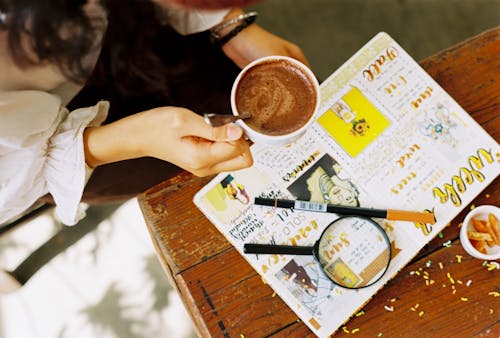 Person Holding Filled Cup Near Table