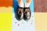 糖果在彩绘地板上，旁边是一双黑色皮鞋，采用高角度拍摄