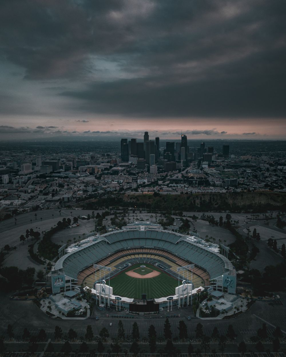 Aerial view of a ballpark at dusk with the city skyline behind it — photo by Leon Macapagal on Pexels