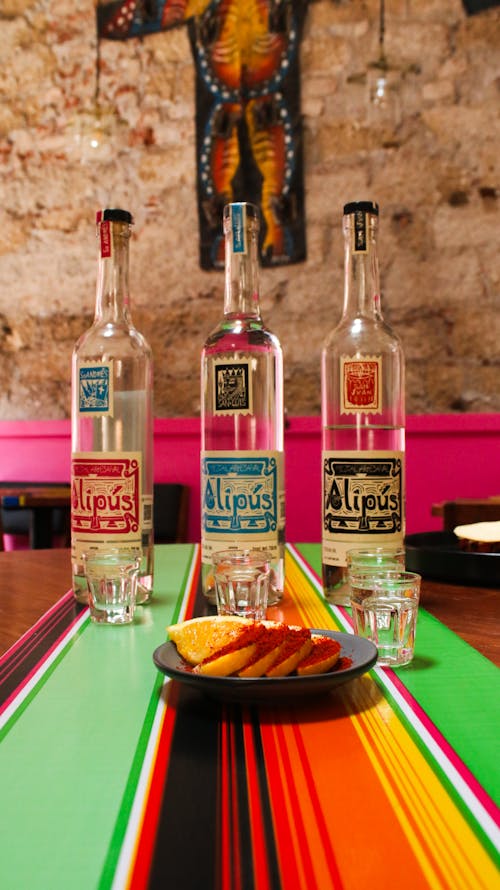 Three bottles of tequila sit on a table with a plate of food