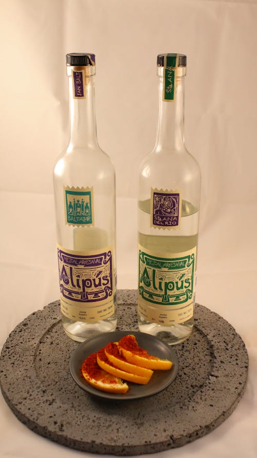 Two bottles of alcohol with oranges on a plate