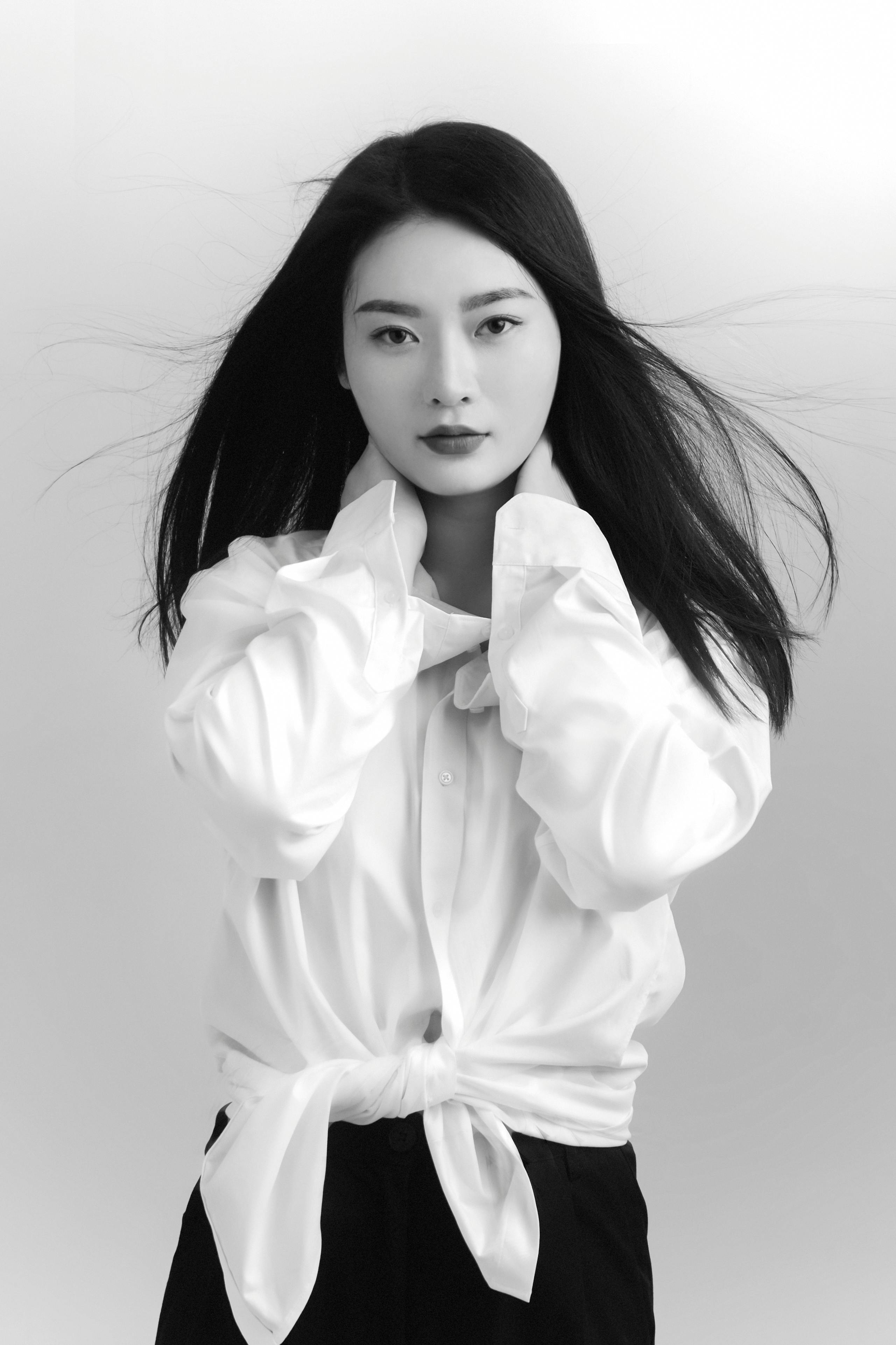Striking black and white portrait of a woman in a stylish pose with flowing hair.